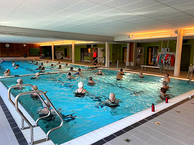 Deltagare i vattenträning i bassängen på Himlabadet, med ledare vid bassängkanten